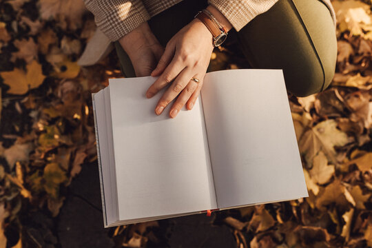 Woman hands holding an open blank book in autumn.