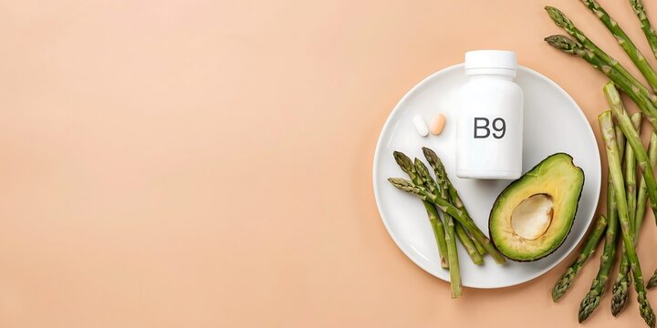 White bottle labeled b9 with asparagus and halved avocado on a plate, down view vitamin