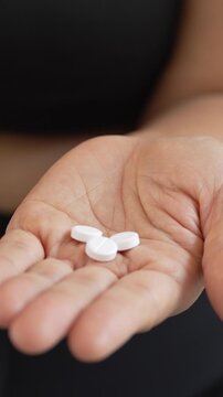 close up woman hand holding a medicine, with pours the pills out of the yellow orange medicine bottle. Stop drug use Taking Medication Caring for the health care medical concept.	