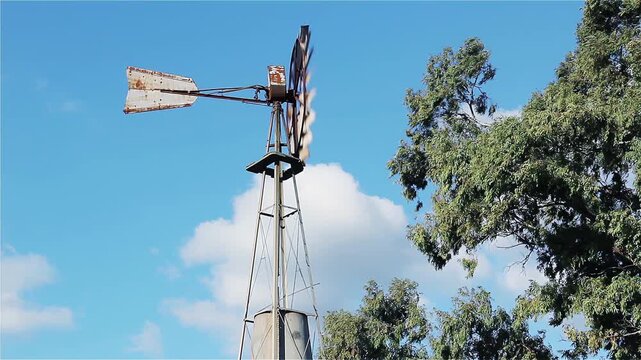 Traditional Farm Windmill Spinning In The Wind Against Blue Sky - 4K