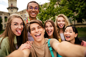 Fototapeta premium Group of happy students taking a playful selfie on a college campus, laughing friends enjoying time together outdoors