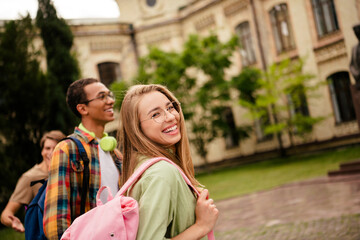 Smiling students with backpacks walking on a university campus, diverse friends enjoying an outdoor...