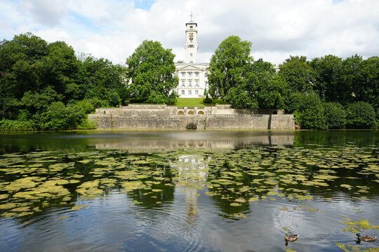 Scenic View Of Trent Building At University Of Nottingham Reflected In Highfields Park Lake With Ducks And Green Plants Under A Cloudy Sky In Nottingham, England.