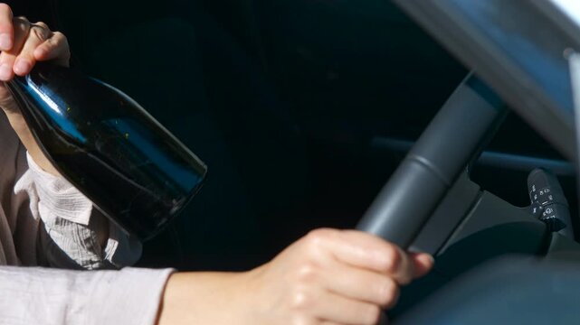 Woman drinking wine while driving a car. Reckless female driver consuming wine directly from bottle while operating vehicle, highlighting extreme danger of impaired driving and road safety risks