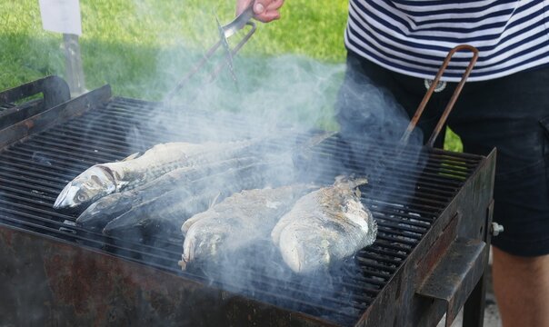 Fisherman grilled fresh fish from the sea on a barbecue, smoked, and healthy Mediterranean food