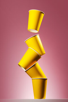 Floating yellow paper cups on pink background
