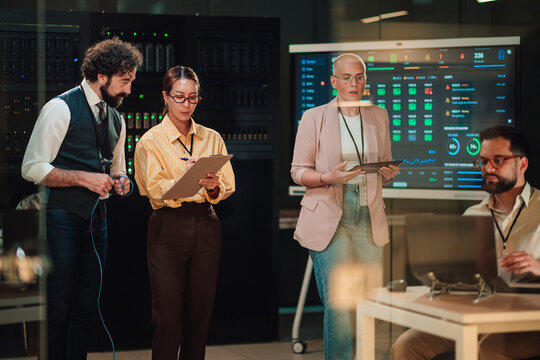 It professionals analyzing data in server room, managing network security and maintaining digital infrastructure services