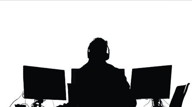 Gamer wearing a headset sits in front of two computer monitors while concentrating on a digital interface.