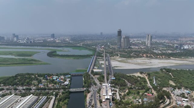 Aerial drone view of Kalindi Kunj Bridge over Yamuna River with Delhi Metro and Noida skyline, India