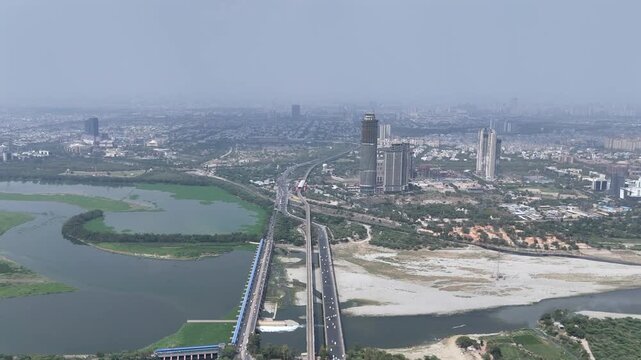 Aerial drone view of Kalindi Kunj Bridge over Yamuna River with Delhi Metro and Noida skyline, India
