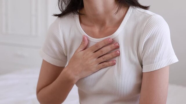The young woman placed her hand over her breasts while touching them because of sudden physical pain or emotional stress.