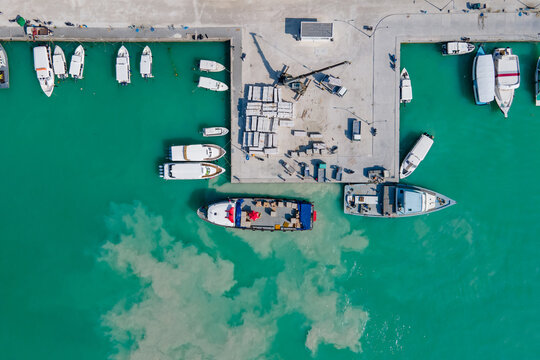 Aerial view of tour boats and logistic boats parking over turquoise water in the jetty at Maafushi island. Nautical vessel transportation system for travel and shipping industry in Maldives