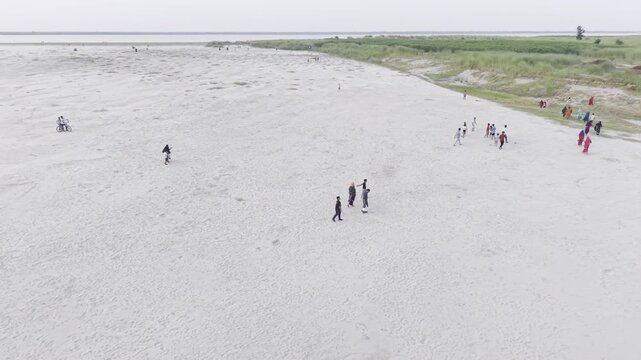 KUSHTIA, BANGLADESH &ndash; JUNE 27, 2026: High-angle drone footage capturing people walking along the expansive sandy riverbank at the Gorai Confluence in Kushtia, Bangladesh.
