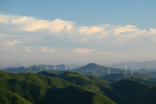 Wind Turbine Farm on a Forested Mountain Ridge at Golden Hour. Wind turbines generate clean renewable energy.	