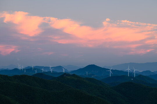 Wind Turbine Farm on a Forested Mountain Ridge at Dusk. Wind turbines generate clean renewable energy.	