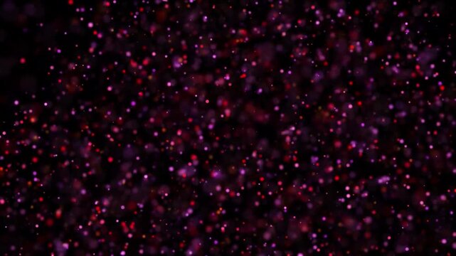 Red and pink sparkling particles on a dark background, creating a festive and enchanting visual effect