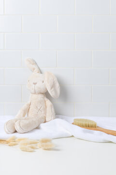 Baby product mockup background with cute plush bunny toy on white bathroom counter. Empty space for newborn skincare, shampoo, or baby cosmetic display.