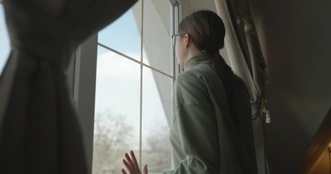 Thoughtful Girl Stand Near Window and Look Outside. 4K 10-bit