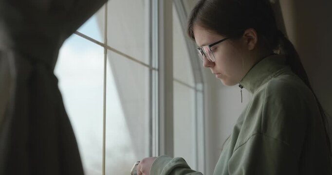 Thoughtful Girl Stand Near Window and Look Outside. 4K 10-bit