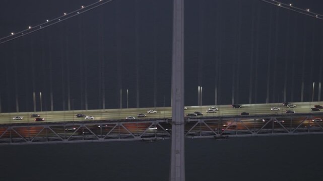 Glowing Traffic Moving Across San Francisco Bay Suspension Bridge At Night - Cinematic Aerial Shot