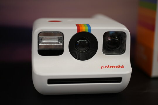 A close up of a white Polaroid instant camera with rainbow stripes.