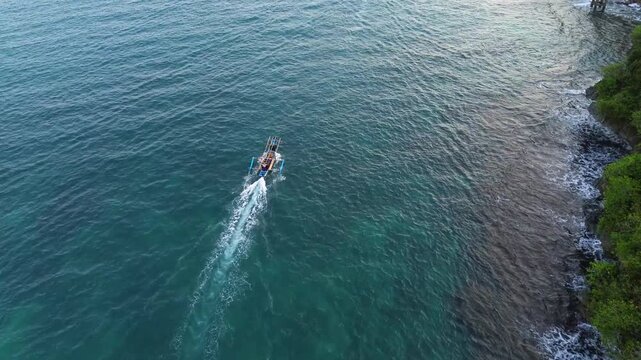 Aerial drone footage of a traditional fishing boat sailing across the vast open ocean. Cinematic aerial perspective capturing the vessel moving through deep blue waters with gentle waves