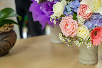 Obraz premium Colorful flower bouquet pink rose white rose purple hydrangea yellow rose daisy gerbera green leaf ceramic vase wooden table indoor natural light cheerful mood