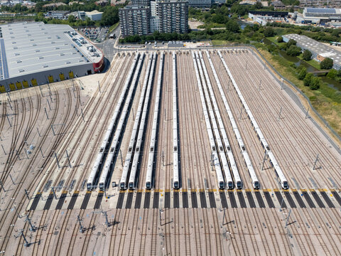 Aerial view of Old Oak Common Elizabeth Line Depot featuring multiple trains parked in parallel on tracks next to a large industrial warehouse in London, England, United Kingdom.
