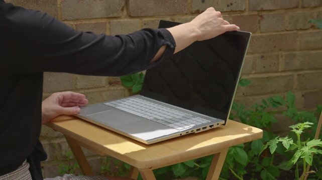 Over Elbow Back View Woman Opening and Typing on Laptop in Garden Shade