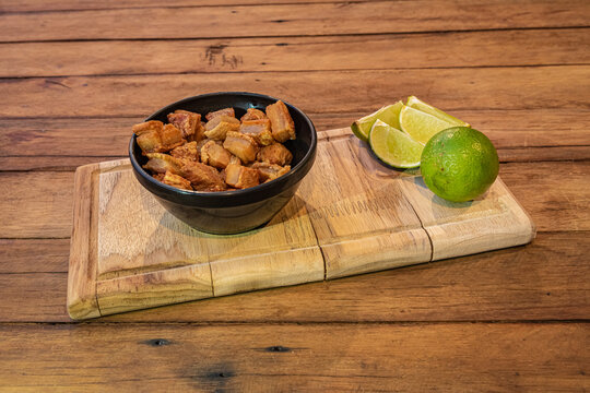 Brazilian torresmo - Crackling Pork Belly and Lime on Wood Board