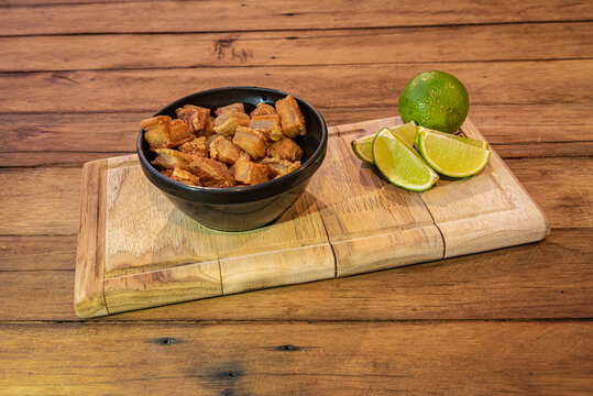 Brazilian torresmo - pork belly crackling with lime on wood