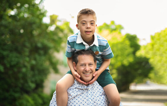 cute little child with trisomy 21 syndrome outside in summer season with his father
