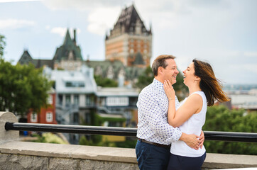 Fototapeta premium Romantic couple in love looking each other while embracing in front of chateau frontenac quebec
