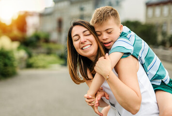 Fototapeta premium cute little child with trisomy 21 syndrome outside in summer season with his mother