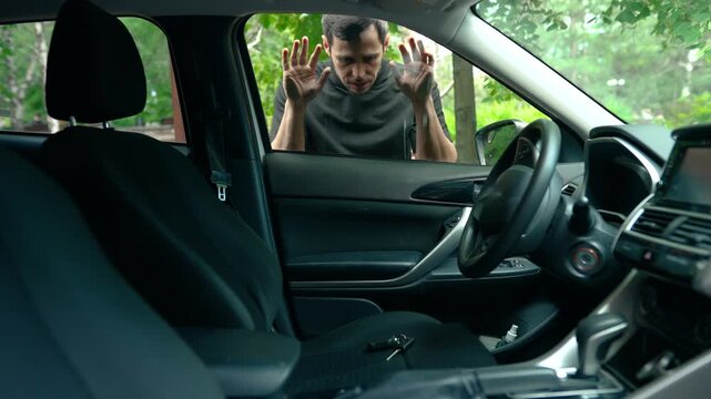 Frustrated man looking at keys forgotten inside his locked car from outside