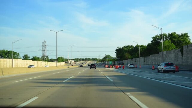 Wide POV shoot of driving on a multi lane highway with moving vehicles, and construction infrastructure during daytime 