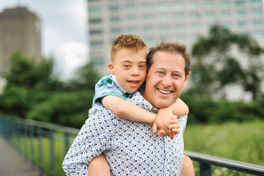 cute little child with trisomy 21 syndrome outside in summer season with his father