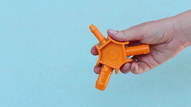 Plumbing tool for calibrating plastic pipes in a woman's hand. Manual calibrator for metal-plastic pipes (16-20-25 mm) with knives for chamfering. Orange plastic calibrator of three-beam design