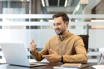 Obraz premium Business man interacting during a video call on a laptop, engaging online with clients or team members from a modern office workspace