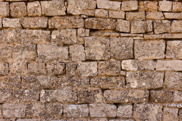 Fototapeta premium Traditional weathered stone wall. The irregular gray and brown blocks create a rugged, rustic architectural texture backdrop.