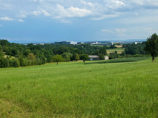 Fototapeta premium germany, scenic summer landscape overlooking ostfildern scharnhausen industrial buildings framed by green meadows forest and quiet rural road