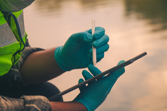 Environmental researchers collecting freshwater samples to monitor pollution and save the information on the tablet.
