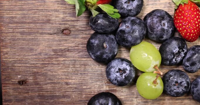 Fresh ripe Blueberry strawberry grape macro closeup on wood dark white background slide move organize