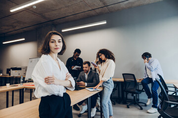 Naklejka premium Confident female leader standing in modern office with diverse team working
