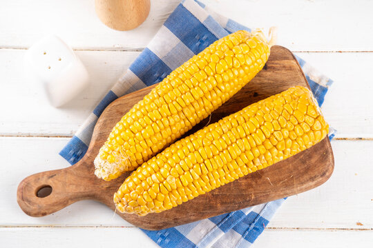 Sweet boiled corn cobs portions on plate, with salt and spices