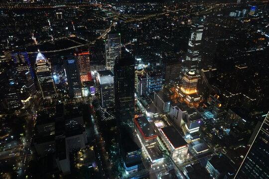 Aerial night view of a bustling modern metropolis with glowing skyscrapers and vibrant city lights illuminating the urban skyline 