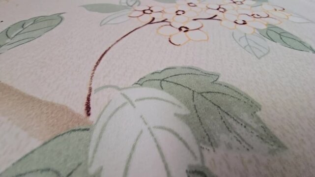 Close-up of a delicate white flower pattern with soft green leaves printed on a textured fabric surface, ideal for textile design, interior decoration, and artistic wallpaper backgrounds, elegant bota