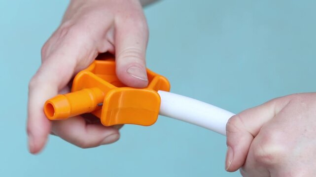 Preparing PEX pipe with orange three-sided chamfering tool. Using hand calibrator to prepare metal-plastic pipe for installation. Close-up of hands while working. Plumbing work