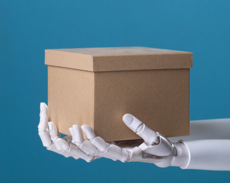 Two white mechanical hands holding a kraft paper parcel box on a blue background