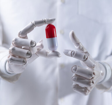 Robot doctor hand holding a red and white capsule pill close up.